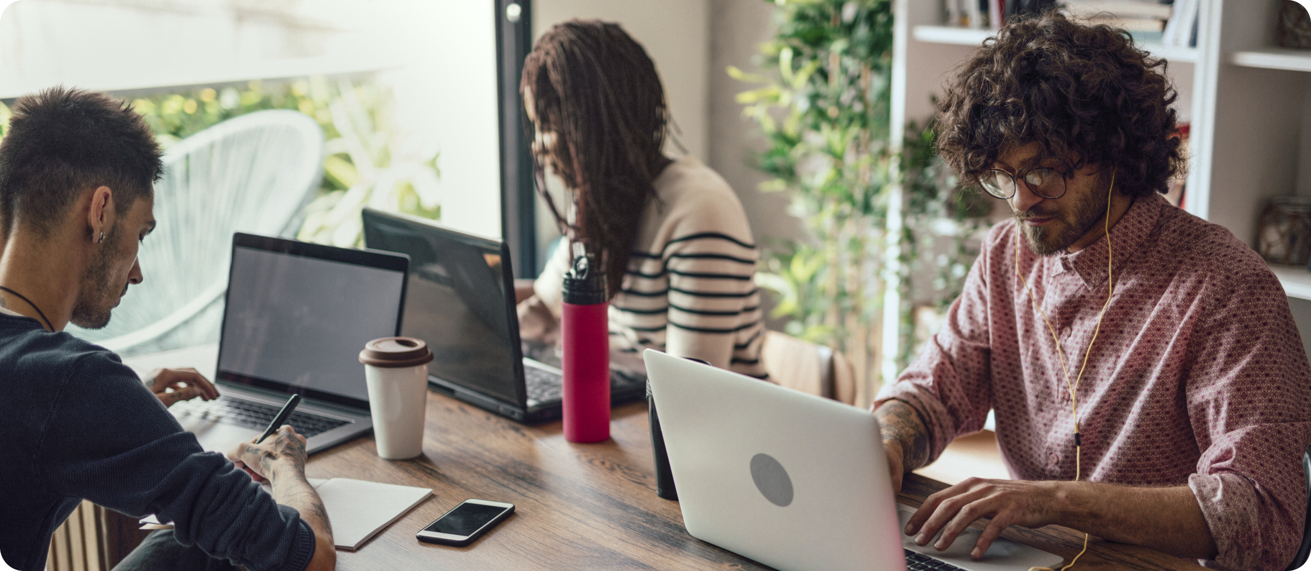 Image of a group of people working on their laptops in a cafe.