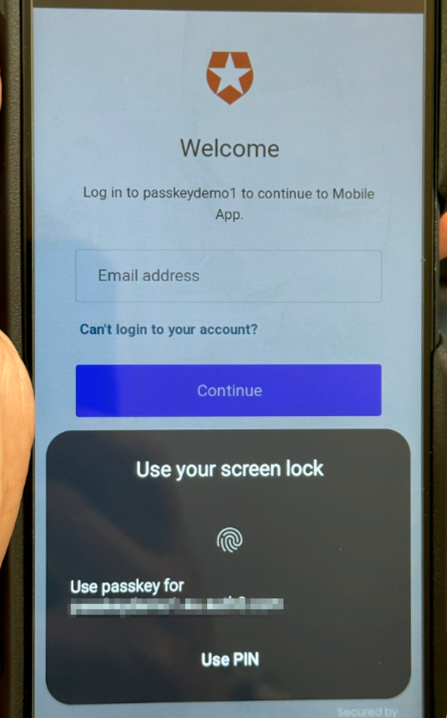A smartphone displays a login screen for a mobile app, prompting the user to enter their email address. 