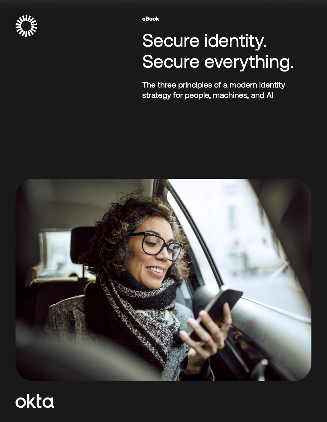 You said Create a short alt text of the attached image  Gemini said An ebook cover for Okta features the text "Secure identity. Secure everything. The three principles of a modern identity strategy for people, machines, and AI," with an image of a smiling middle-aged woman with curly hair and glasses using her phone while riding in a car.